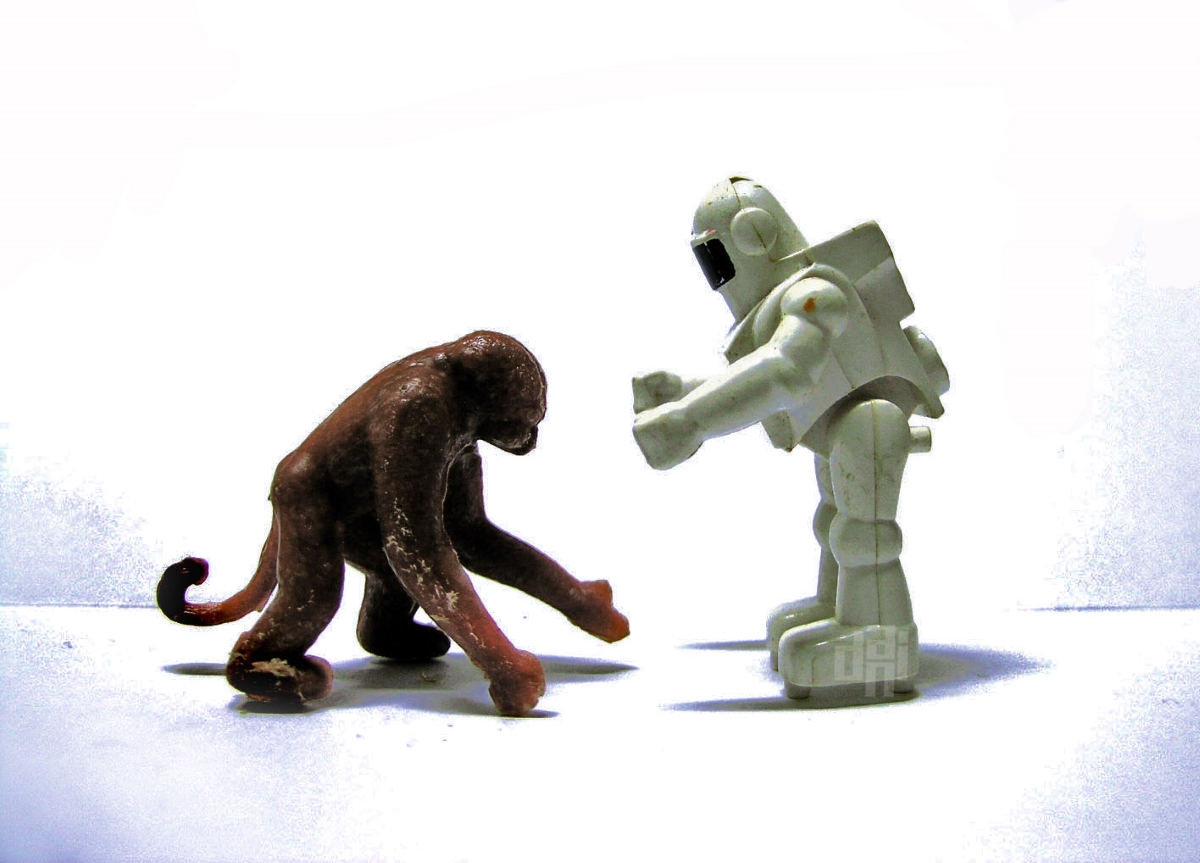 (Image) A toy robot greets a toy chimp in front of a white background.