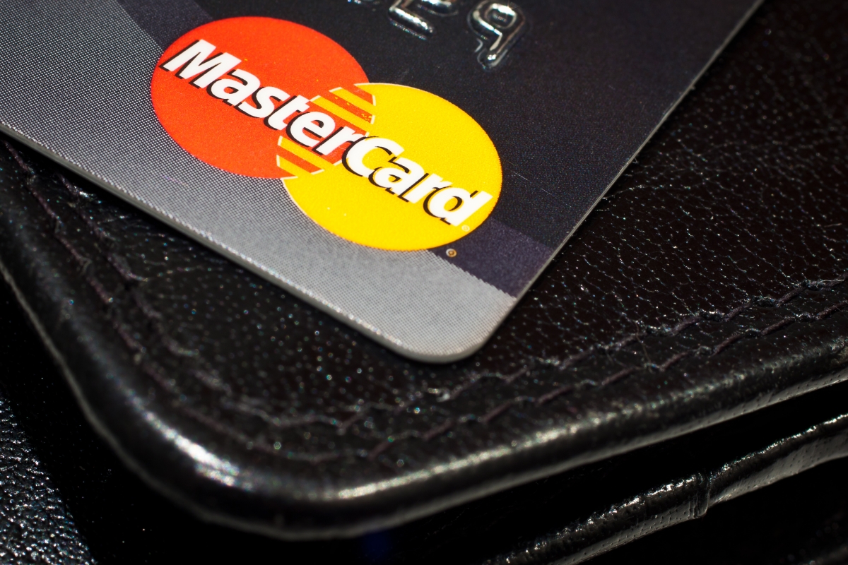 Image: A credit card sits on top of a black leather wallet.