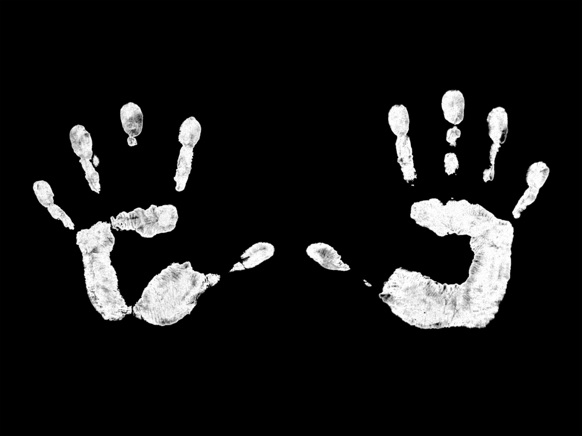 Image: White handprints on a black background.