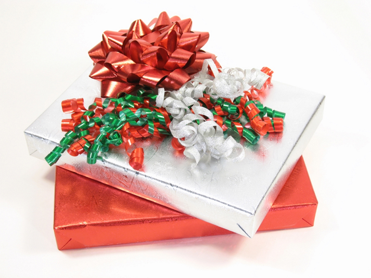 (Image) A stack of three gifts, topped with a large bow, in front of a white background.