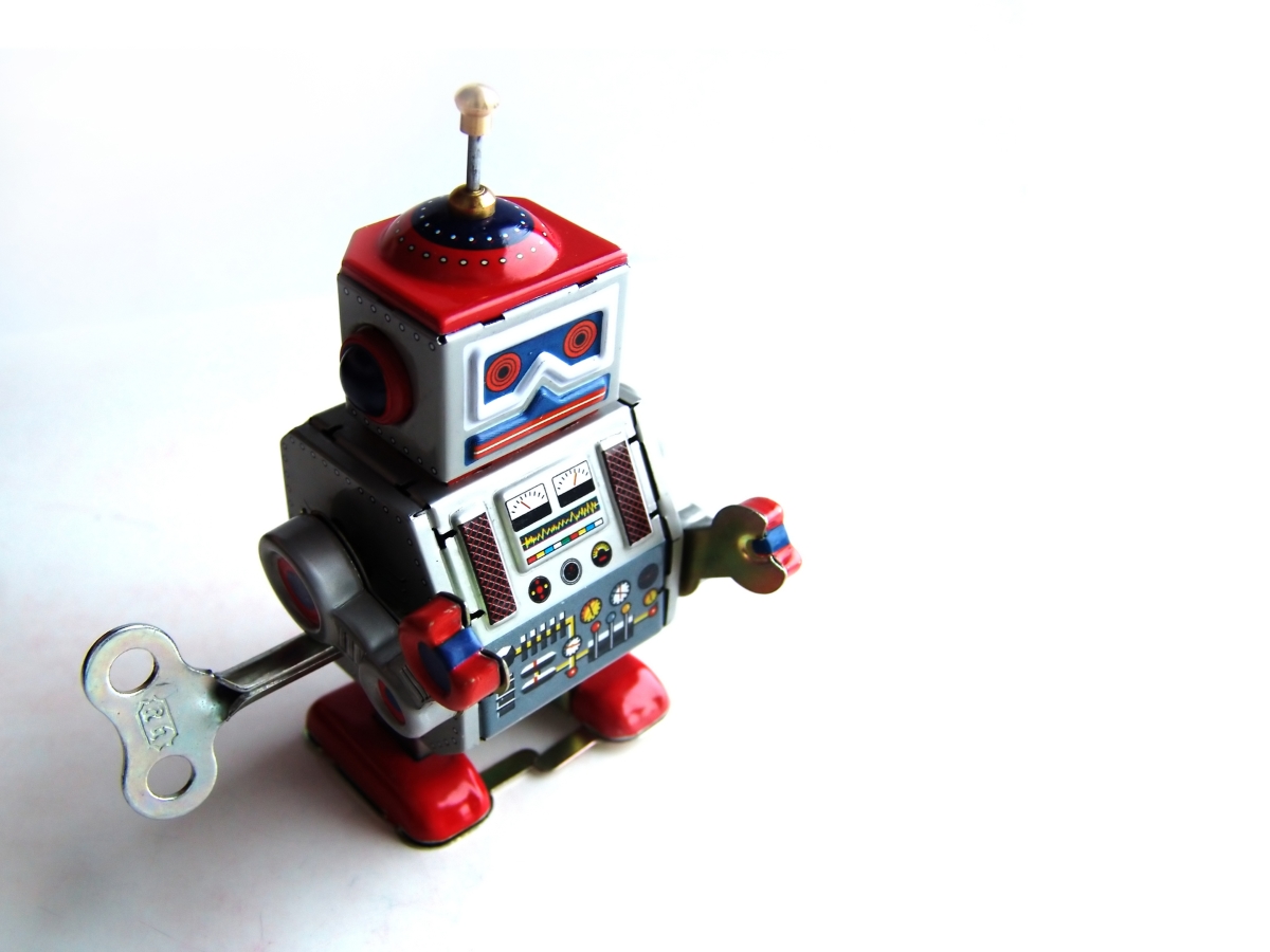 (Image) A small, metal toy robot with a wind-up mechanism, in front of a white background.