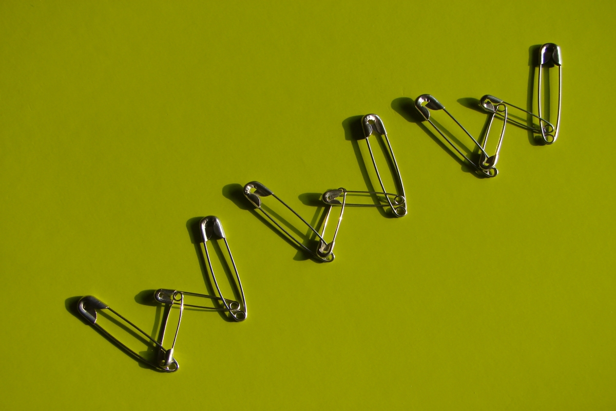 A cluster of safety pins spells out 'WWW' on a green background.